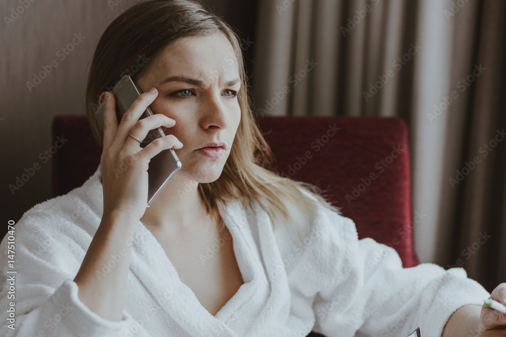 beautiful woman in bathrobe speaking on the smartphone in hotel room beautiful woman in bathrobe speaking on the smartphone in hotel room