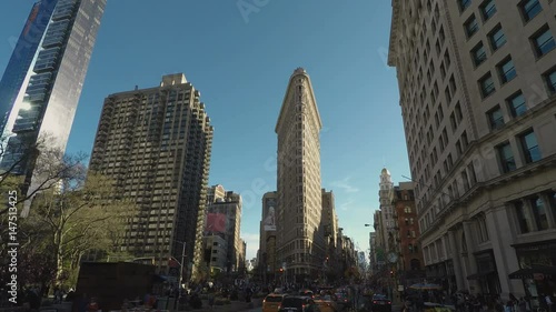 New York, USA Flatiron Building day view facade in Manhattan.
External view of the Fuller Building, a 22-story triangular skyscraper on a busy day with traffic at 5th Avenue.
