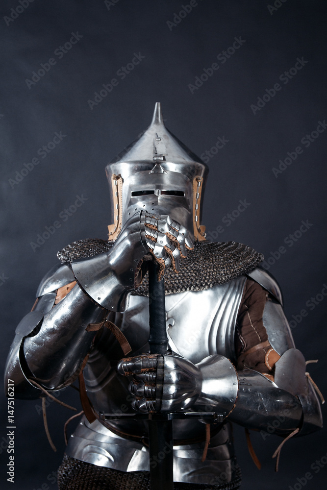 A medieval warrior in a helmet and with a sword. Knight on dark background A medieval warrior in a helmet and with a sword. Knight on dark background