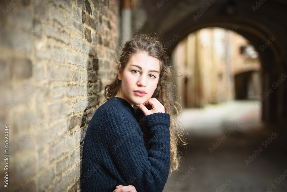 Very attractive blond girl pensive under the arches in the alley.