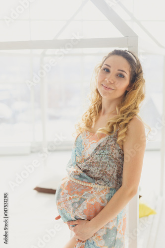 Young beautiful pregnant woman standing near window at home