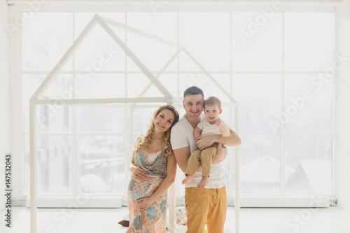 Happy Family: Pregnant mother with father and little boy, Against the window in a bright room