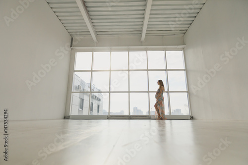 Pregnant woman stands by the window