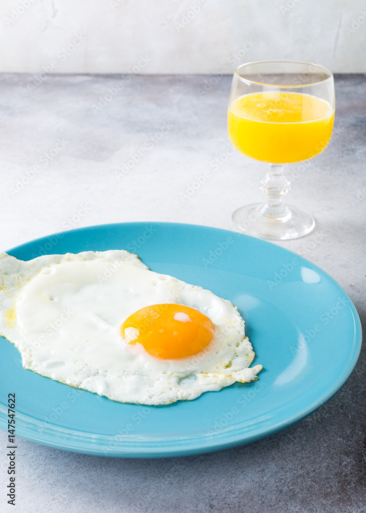 Fried egg on blue plate and orange juice. Healthy breakfast concept with copy space. Fried egg on blue plate and orange juice. Healthy breakfast concept with copy space.
