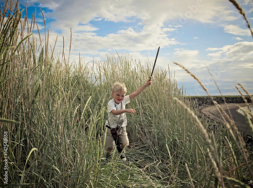 Boy playing with sword in wheat field photo