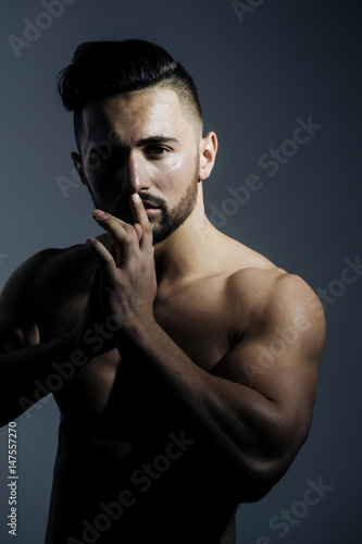 Sexy athletic man posing with muscular hands at handsome face