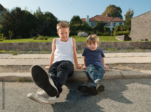 Brothers sitting together on sidewalk photo