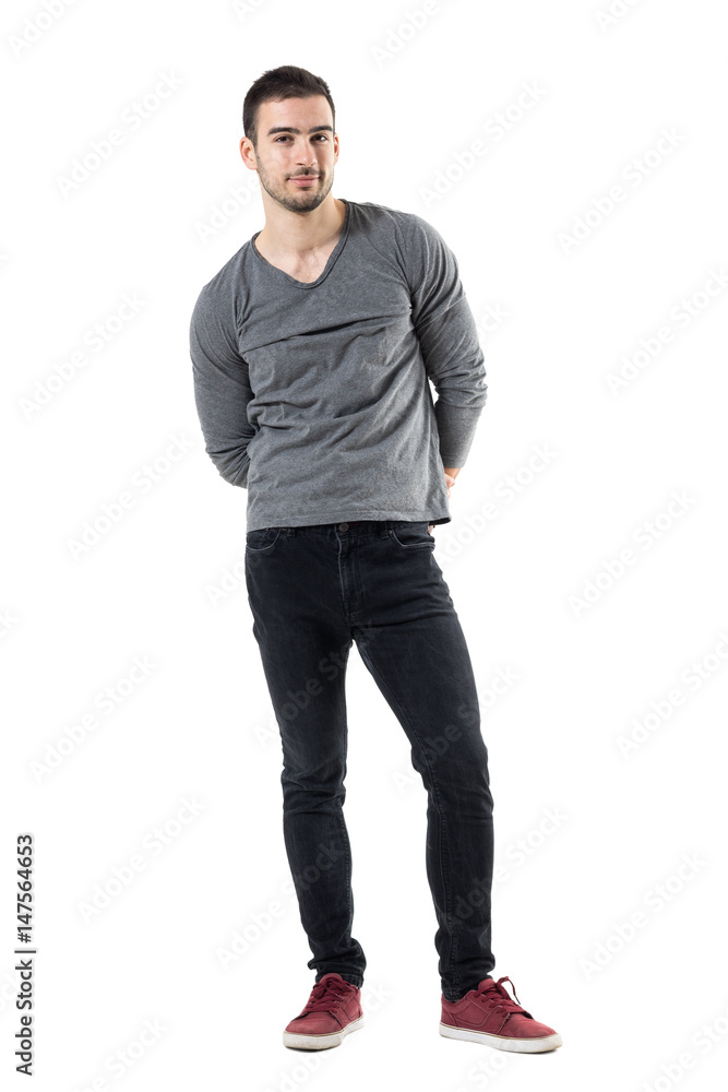 Young handsome casual man with hands behind back smiling at camera. Full  body length portrait isolated over white studio background. Stock Photo