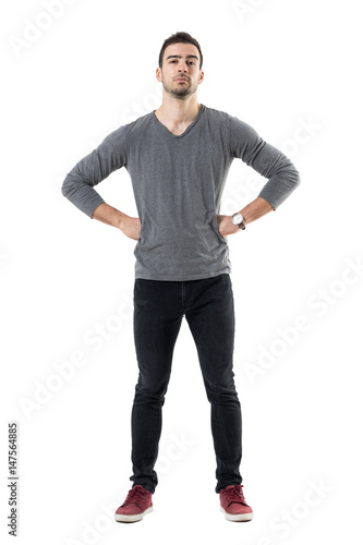 Suspicious distrustful man with hands on hips looking at camera. Full body length portrait isolated over white studio background. © sharplaninac