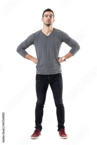 Suspicious distrustful man with hands on hips looking at camera. Full body length portrait isolated over white studio background.