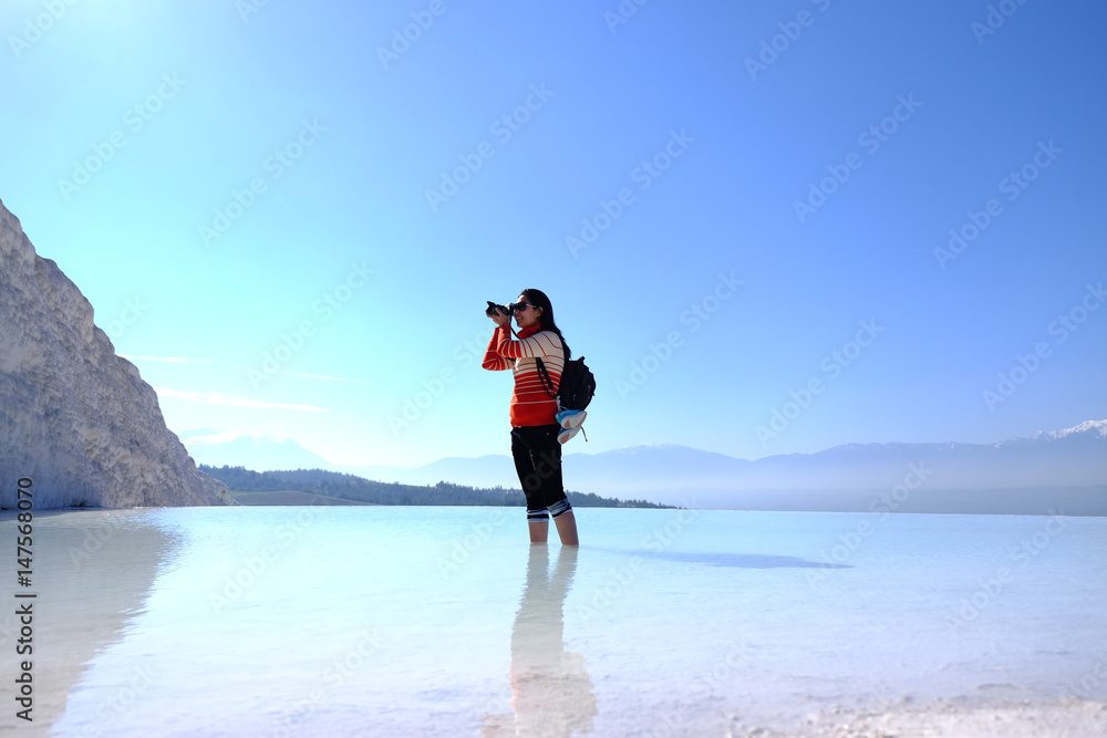 Happy woman take photo standing in the water. the tourist at Pamukkale, Turkey