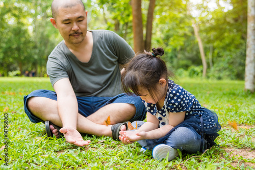 Little asian girl and her father looking at butterflies in park