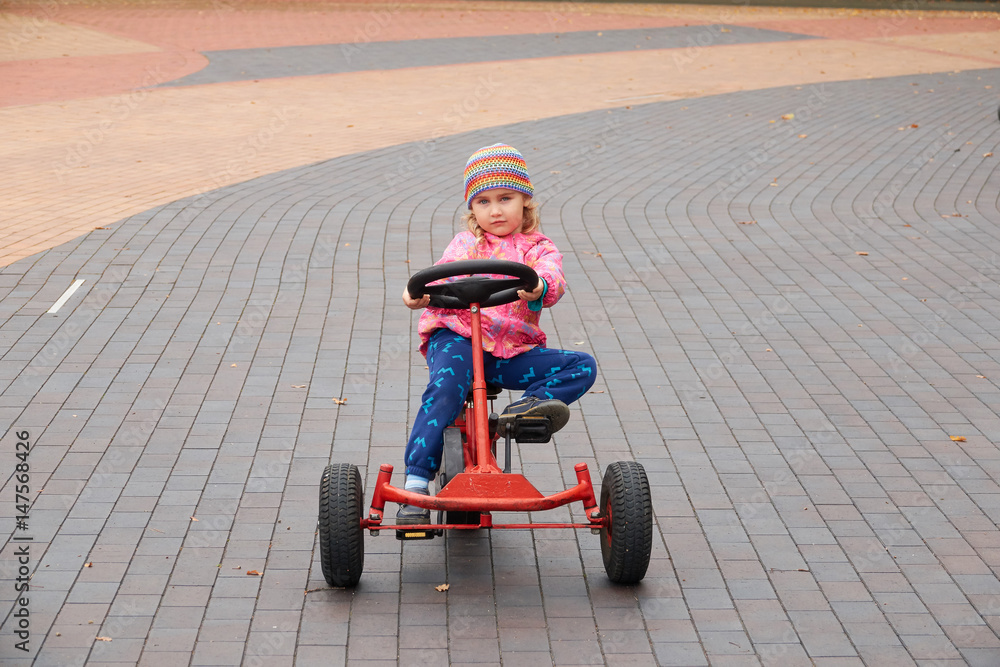 Little girl having fun driving a pedal car in day. Little girl having fun driving a pedal car in day.