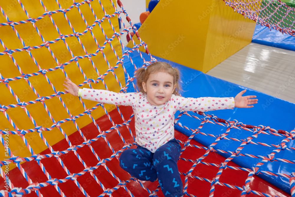 Girl swinging on the Hammock Ropes Course with Long Fair Hair in Indoors Playground. Active Toddler Girl Having Fun At Sport Center Girl swinging on the Hammock Ropes Course with Long Fair Hair in Indoors Playground. Active Toddler Girl Having Fun At Sport Center