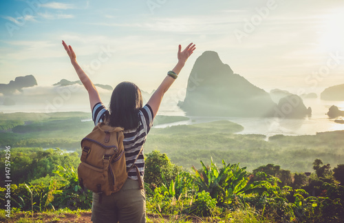 Happy young traveler woman backpacker raised arm up to sky enjoying a beautiful of nature at top of mountain and sea view,Freedom wanderlust concept © weedezign