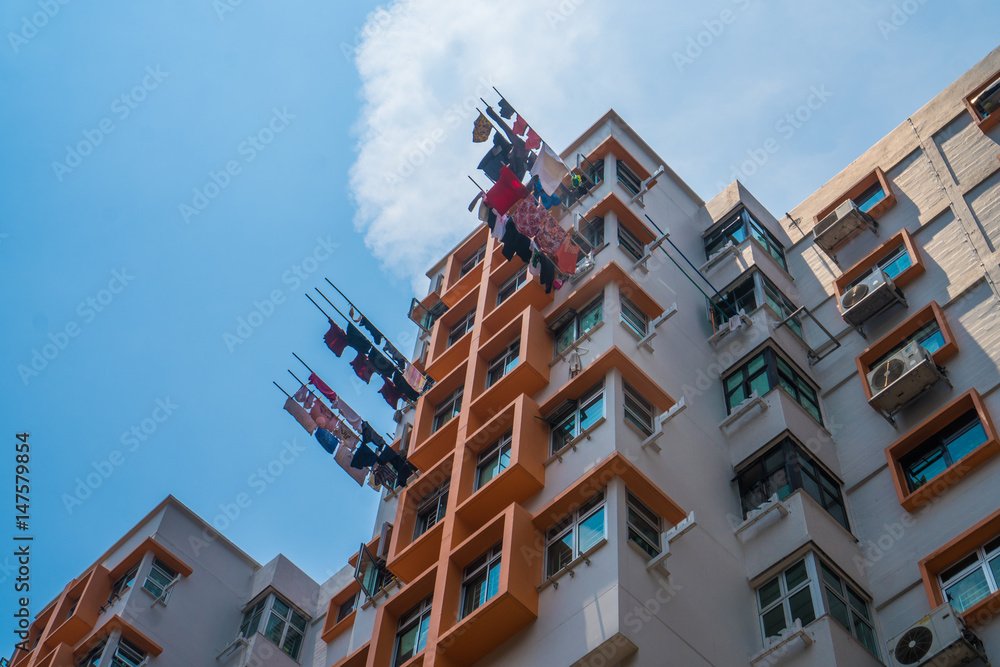 Typical Asian highrise public housing estate with air conditioners and laundry against blue sky