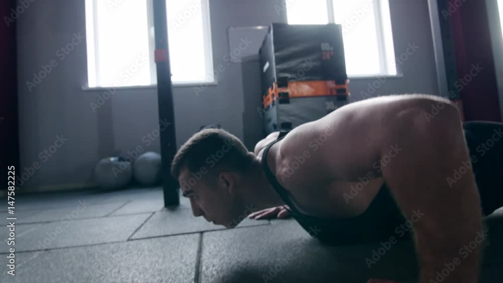Sportsman exercising in the gym. Muscular young man doing pushups on exercise mat.