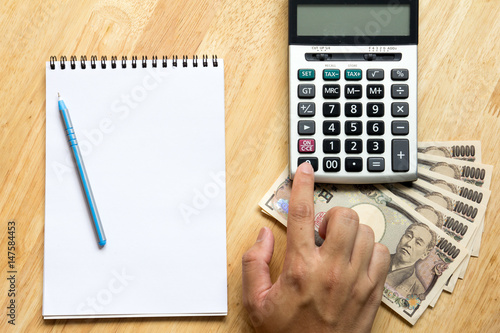 Obraz na płótnie Business man calculate with calculator, and have book, japanese yen banknote on