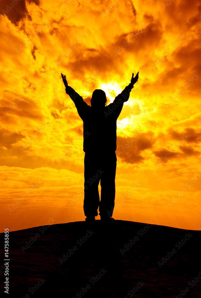 Silhouette of woman with hands rise up and pray with sunlight. Freedom concept.