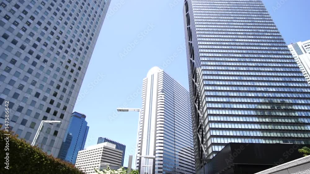 ガッツポーズをしながらジャンプするビジネスマン 快晴 青空 新宿高層ビル街 ガッツポーズをしながらジャンプするビジネスマン 快晴 青空 新宿高層ビル街