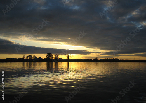 Fototapeta Naklejka Na Ścianę i Meble -  Sunset on the river in the background of the village