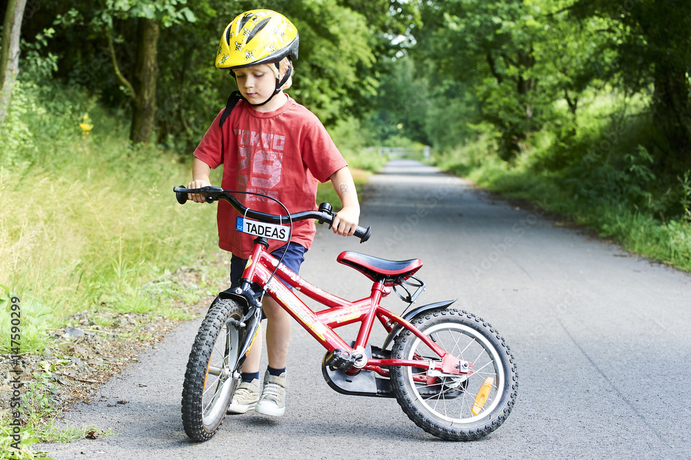 Young boy riding bicycle on a summer day at asphalt road. Bicycle path Young boy riding bicycle on a summer day at asphalt road. Bicycle path