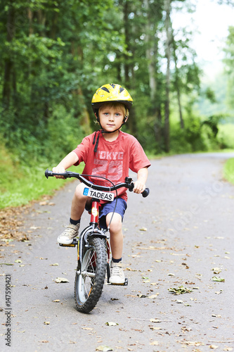 Young boy riding bicycle on a summer day at asphalt road. Bicycle path © Petr Bonek