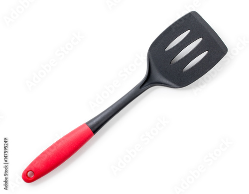 Black plastic kitchen spatula with red handle isolated on a white background. Top view, close up.