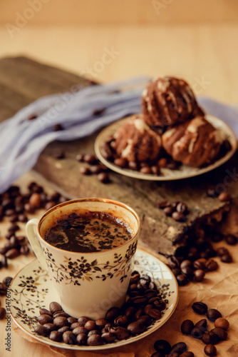 Sweet cake with a cherry and coffee beans on background of cup of coffee and warm knitted scarf. Tasty food background. Cozy winter breakfast. Good morning.