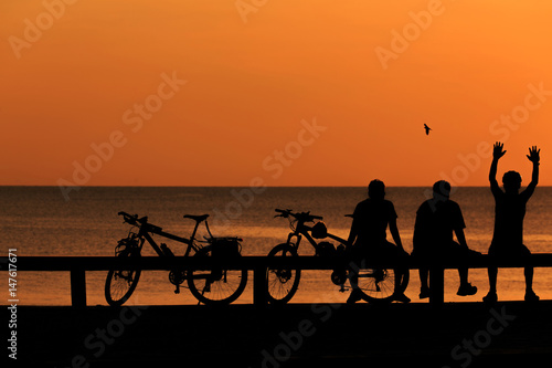 Silhouette man and bike relaxing with sun flare over the beach