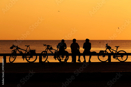 Silhouette man and bike relaxing with sun flare over the beach