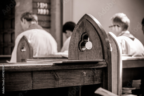 Gothic church pews with priests in the background out of focus. Artistic retro vintage edit. photo