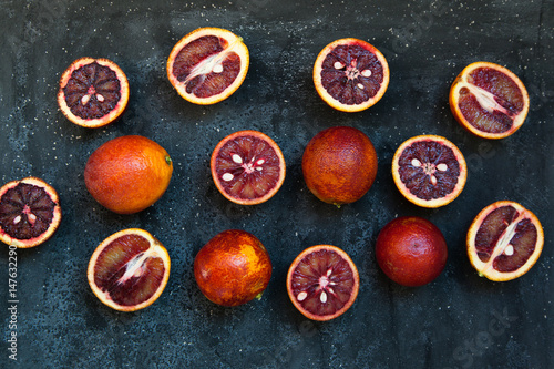 Red Sicilian orange whole and cut on a dark background with branches of rosemary. Daylight  open space for your text.
