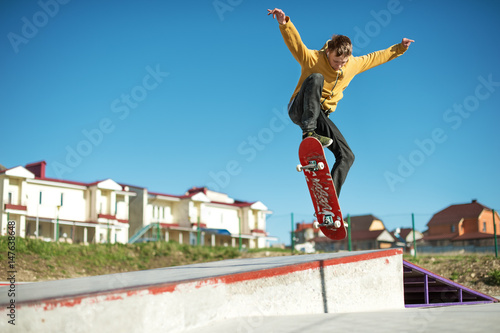 Fényképezés A teenager skateboarder does an ollie trick in a skatepark on the outskirts of t