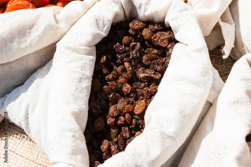 Brown raisins in white cloth bag