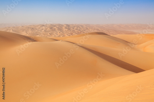 Arab man in traditional outfit sitting on a dune in the empty quarter of the arabian Desert © SELIMBT