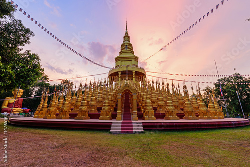 Golden pagoda in WatPaSawangBun Temple in sunset time photo