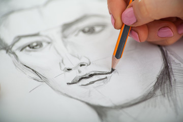 Closeup of drawing man's portrait at the desk