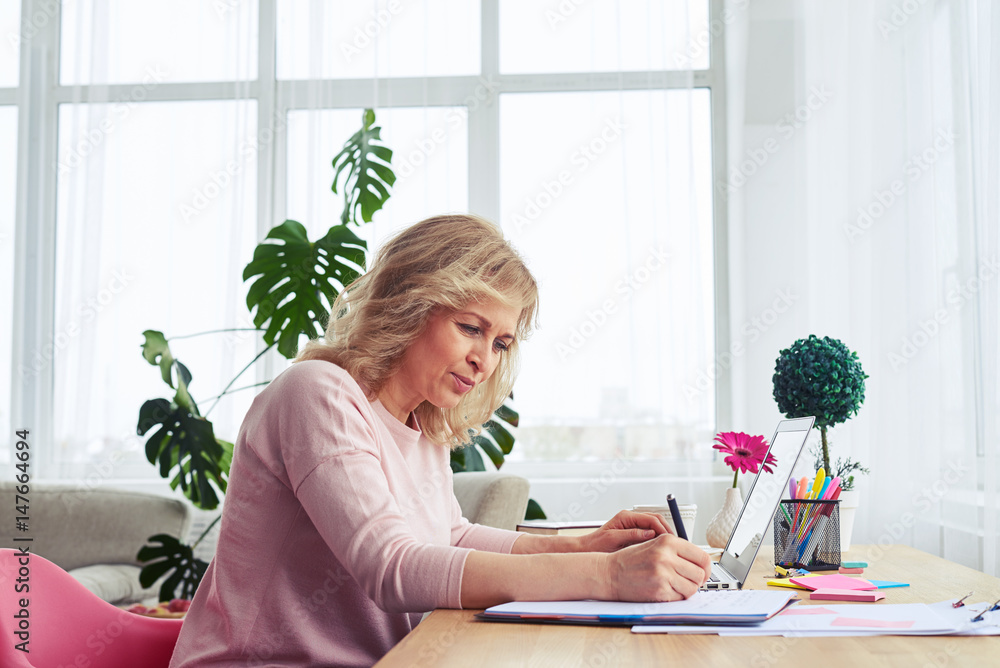 Elegant woman writing while working Elegant woman writing while working