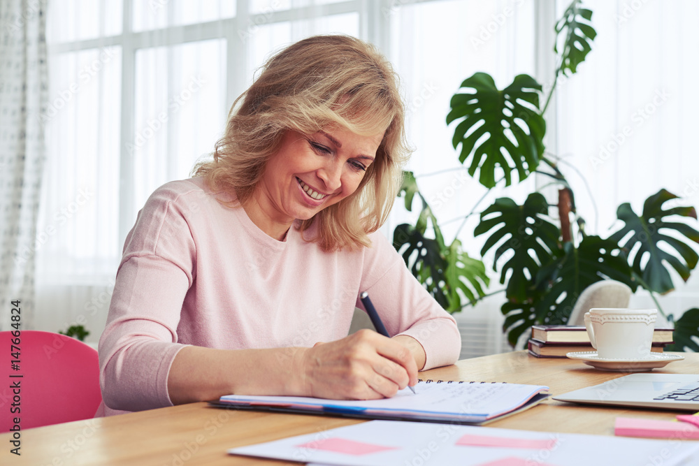 Female with fantastic smile drinking coffee while writing Female with fantastic smile drinking coffee while writing
