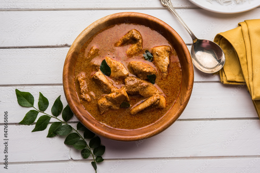 tasty fish curry served with white cooked basmati rice with curry leaves in the background