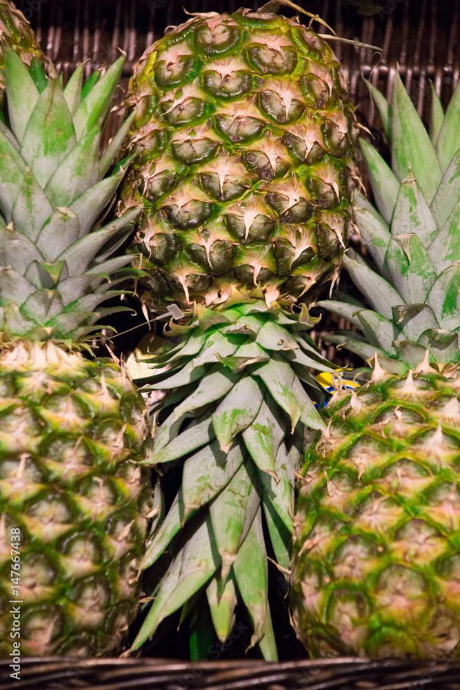 Three fresh pineapples in a basket Three fresh pineapples in a basket