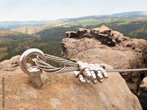 Iron twisted rope stretched between rocks in climbers patch via ferrata. Rope fixed in rock