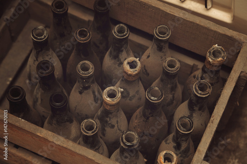 anciennes bouteilles de vin dans caisse en bois dans cave avec poussière
