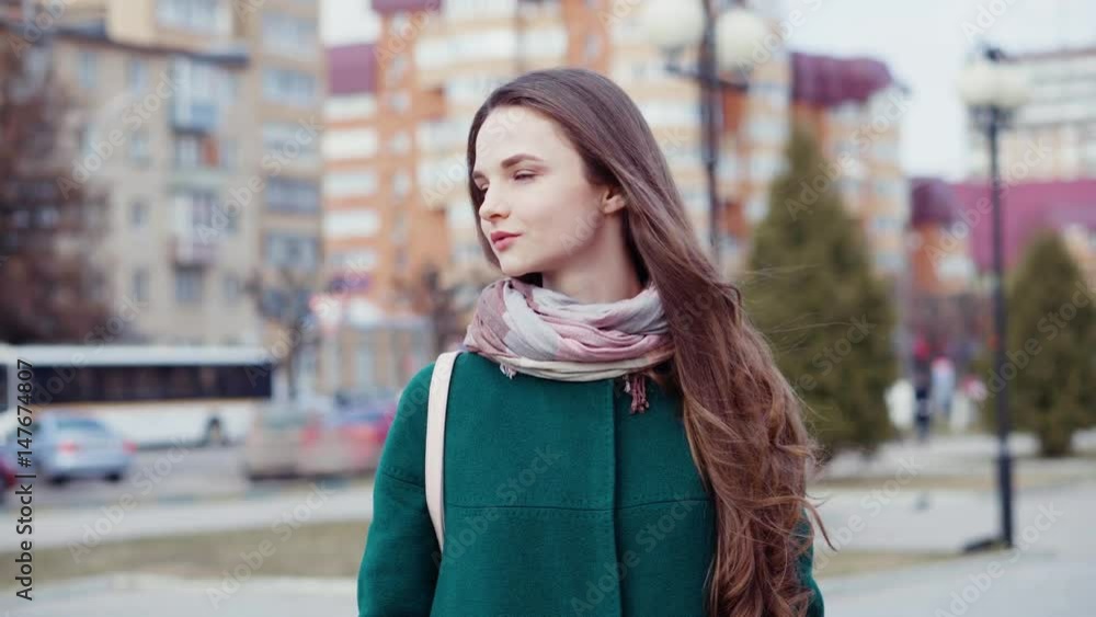 Young long-haired brunette woman in coat on a city street Young long-haired brunette woman in coat on a city street