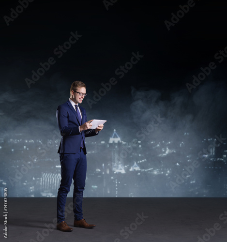 Businessman with computer tablet standing on a night city background.  Job  business  career  concept.