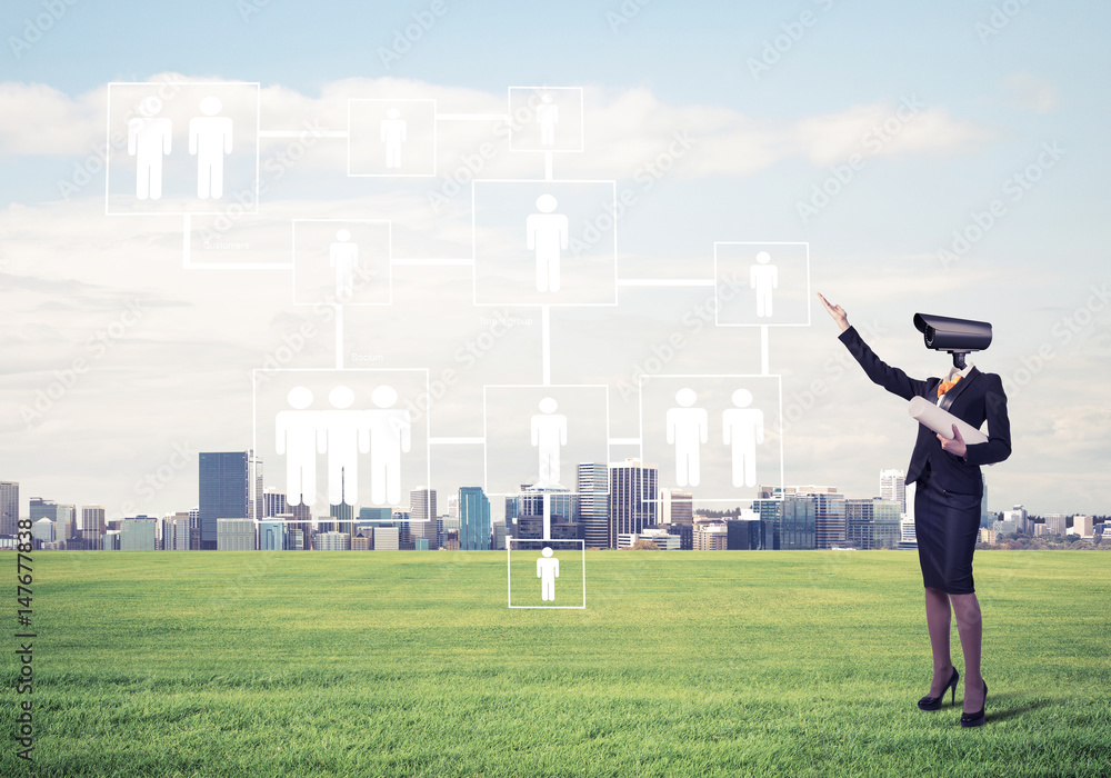 Camera headed woman standing on green grass against modern citys