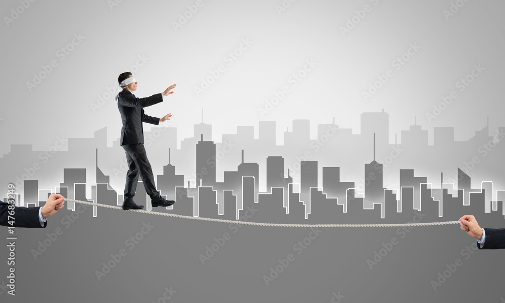Business concept of risk support and assistance with man balancing on rope Business concept of risk support and assistance with man balancing on rope