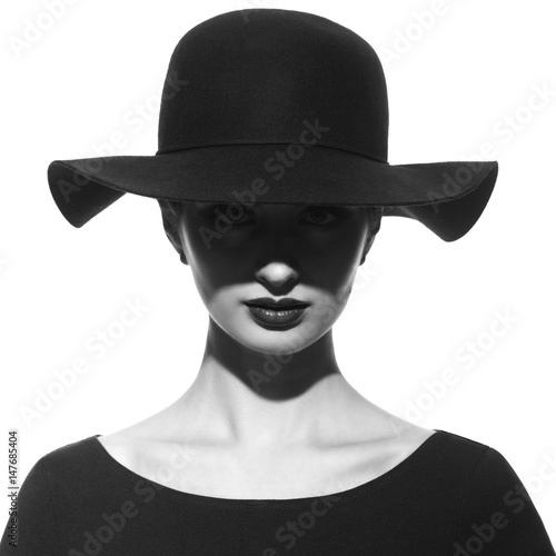 Black and white fashion portrait of a silhouette of a girl in a hat with wide brim with a shadow in front of her eyes.