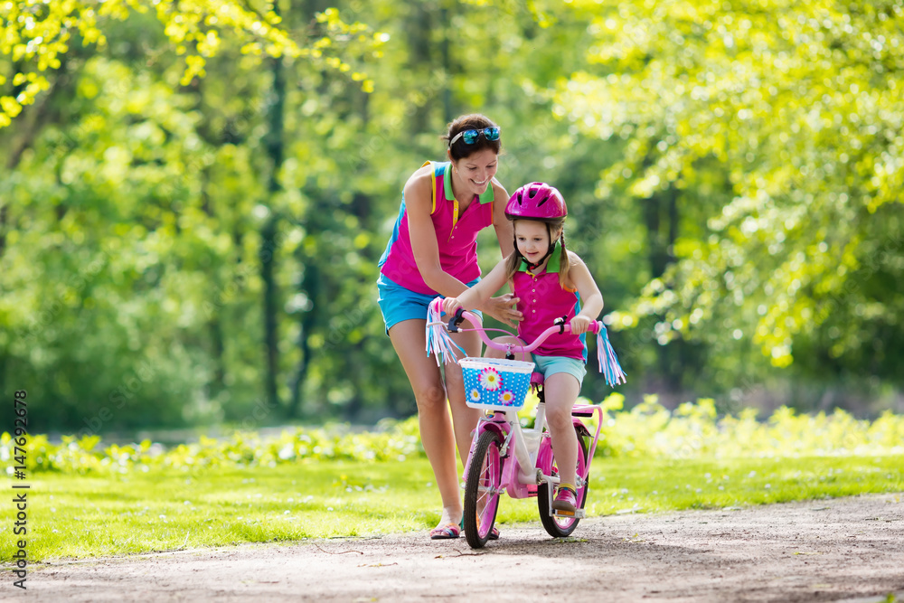 Fototapeta premium Mother teaching child to ride a bike